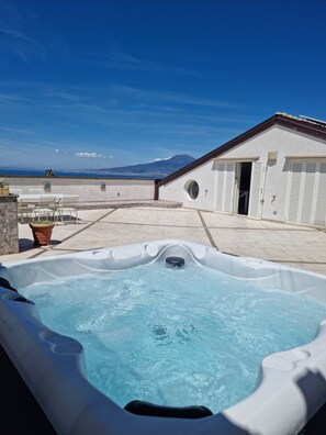 A hot tub on a rooftop terrace with a view of the sea and a mountain in the distance. - Panorama Suite (Vico Equense)