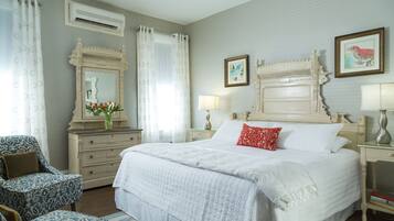 A bedroom with a large bed, a dresser, a chair, and a nightstand with lamps.