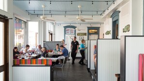 A restaurant with high ceilings, exposed beams, and pendant lighting. - Carroll Villa Hotel (Cape May)
