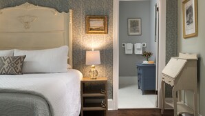 A neatly arranged bedroom with a bed, bedside table, lamp, and a dresser. - Carroll Villa Hotel (Cape May)