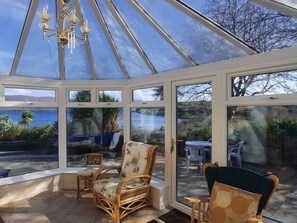 A conservatory with a glass ceiling, wicker furniture, and a view of the sea. - Saoirse (Gortmore)