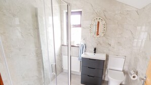 A bathroom with a glass shower enclosure, a sink with a mirror, and a toilet.