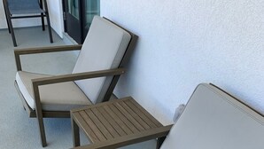 Drei Outdoor-Loungesessel mit Kissen, auf einem strukturierten Boden angeordnet, wahrscheinlich Teil einer Terrasse oder eines Außenbereichs.