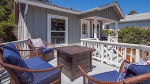 A covered outdoor deck with wicker furniture and a wooden table. - Fantastic, modern 2bdr Cottage, 5min to beach (Santa Cruz)