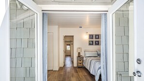 A hallway leading to a bedroom with a bed, bedside tables, and framed artwork on the wall. - Fantastic, modern 2bdr Cottage, 5min to beach (Santa Cruz)