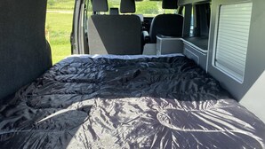 A van interior with a bed, a small table, and a window. - Inviting 2 bed Camper in Holyhead (Holyhead)