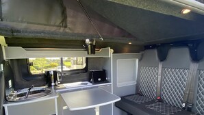 A compact kitchenette with a sink, stove, and small countertop. - Inviting 2 bed Camper in Holyhead (Holyhead)