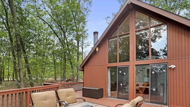 A wooden deck with outdoor furniture, large sliding glass doors, and a forest backdrop. - Simple Pleasures-Woods Golf Resort-Peaceful & Calm (Hedgesville)