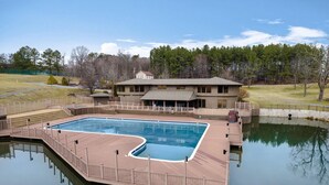 A rectangular swimming pool with a wooden deck and a small building in the background. - Simple Pleasures-Woods Golf Resort-Peaceful & Calm (Hedgesville)
