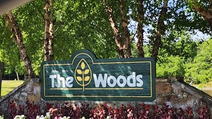 A sign with the text "The Woods" and a leaf symbol. - Simple Pleasures-Woods Golf Resort-Peaceful & Calm (Hedgesville)