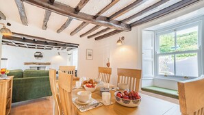 Un comedor acogedor con muebles de madera, un cuenco de fruta y vistas al verdor exterior.