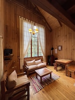A cozy wooden cabin interior with a sofa, a small table, and a television.