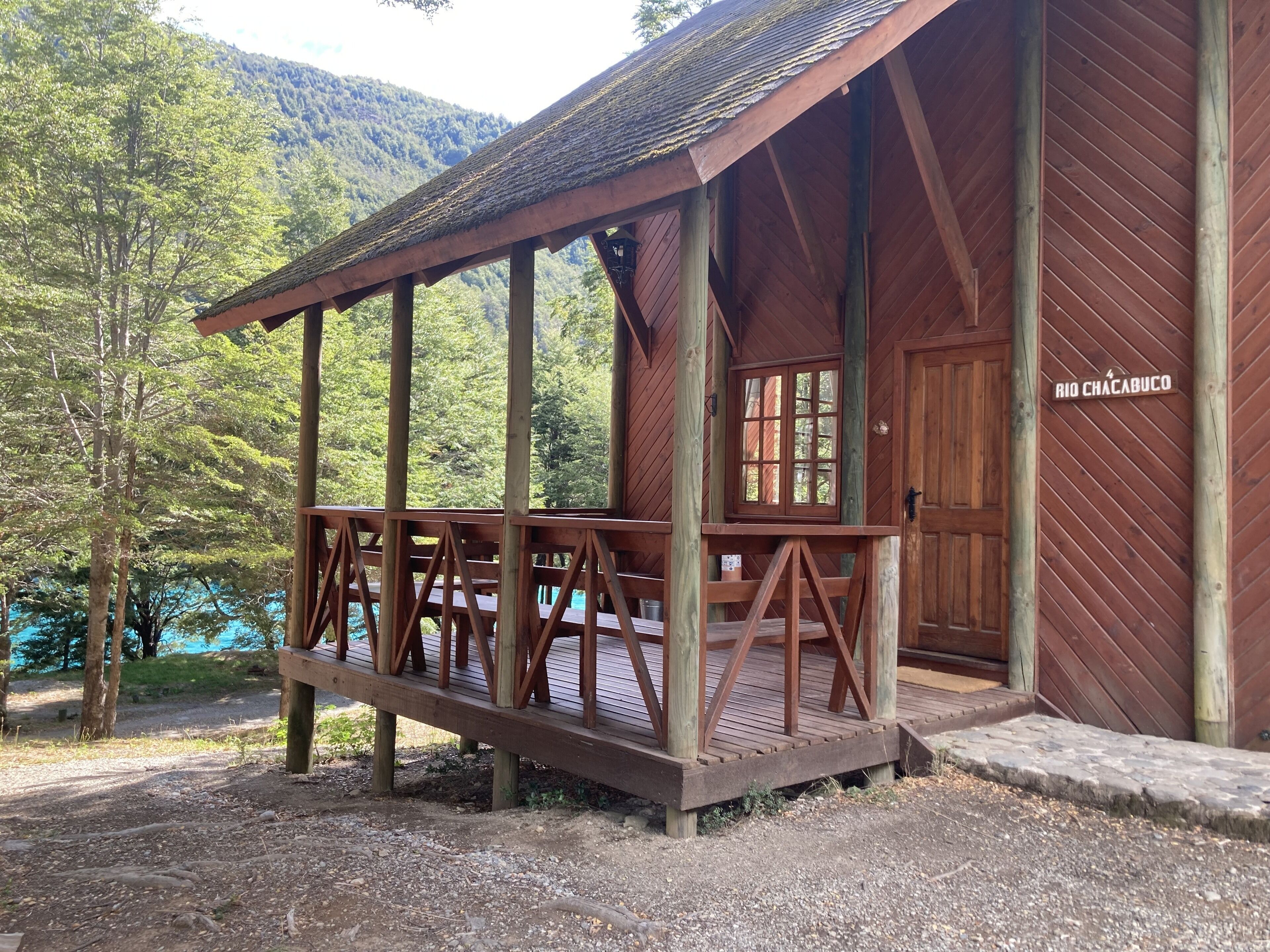 A wooden cabin with a porch, a window, and a door labeled "RIO CHACABUCO".