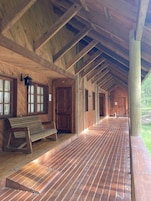 A wooden cabin with a covered porch, wooden benches, and a door labeled "H2".