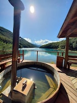 A hot spring area with a wooden deck and a view of a lake surrounded by mountains.
