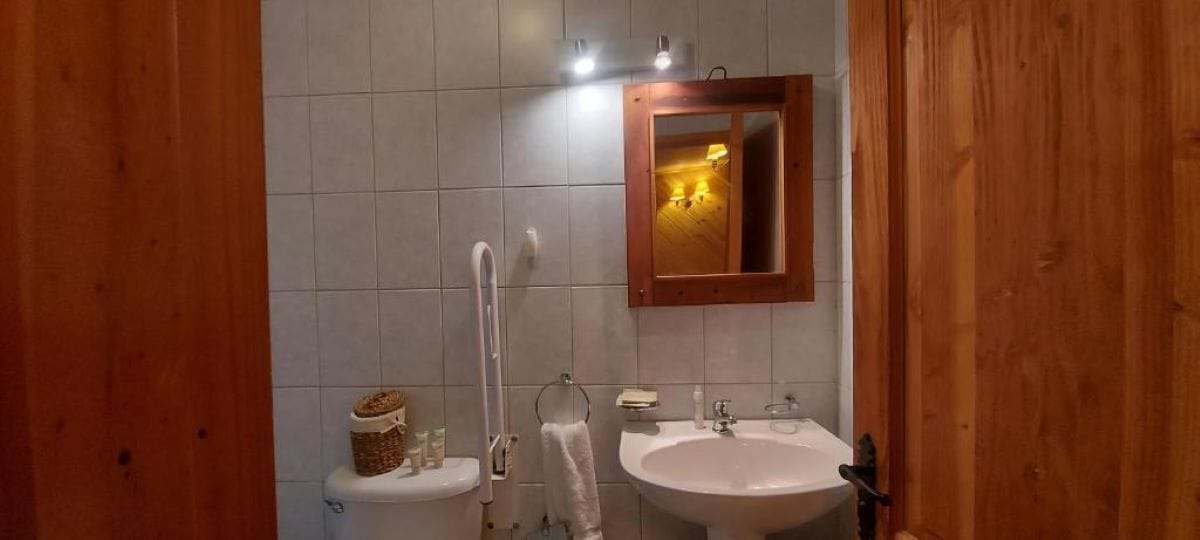 Een badkamer met toilet, bidet, wastafel en houten lambrisering.