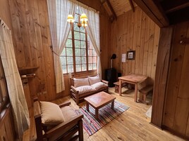 A cozy wooden cabin interior with a sofa, a small table, and a window with curtains.