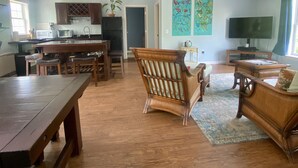 Amplia sala de estar con una mesa de comedor, sillas de madera, un sofá y una televisión.