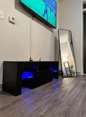 Relax in this stylish living room with a flat-screen TV, entertainment unit, and large mirror.