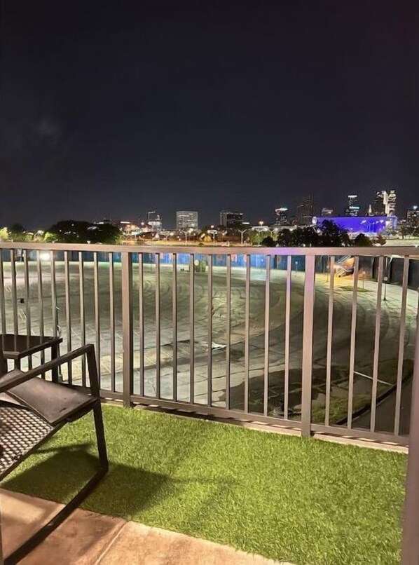 Enjoy the city view from this balcony with a single chair and metal railing.
