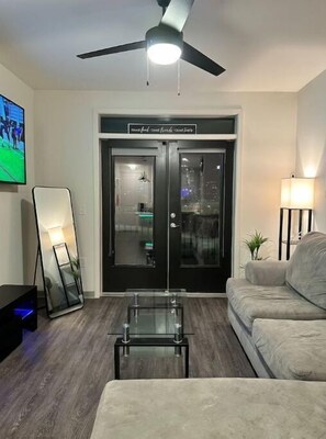 Relax in this stylish living room with a ceiling fan, flat-screen TV, and comfortable sofa.