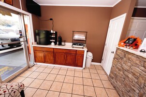 Una kitchenette equipada con refrigerador, cafetera y un lavamanos pequeño.