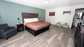 A bedroom with a bed, a chair, a desk, and a mirror.