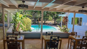 A restaurant with a pool view, outdoor seating, and tropical plants. - Seven Palms Villa  (Runaway Bay)