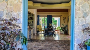 A stone-floored lobby with a dining area, featuring a table and chairs, and a view of the outdoors. - Seven Palms Villa  (Runaway Bay)