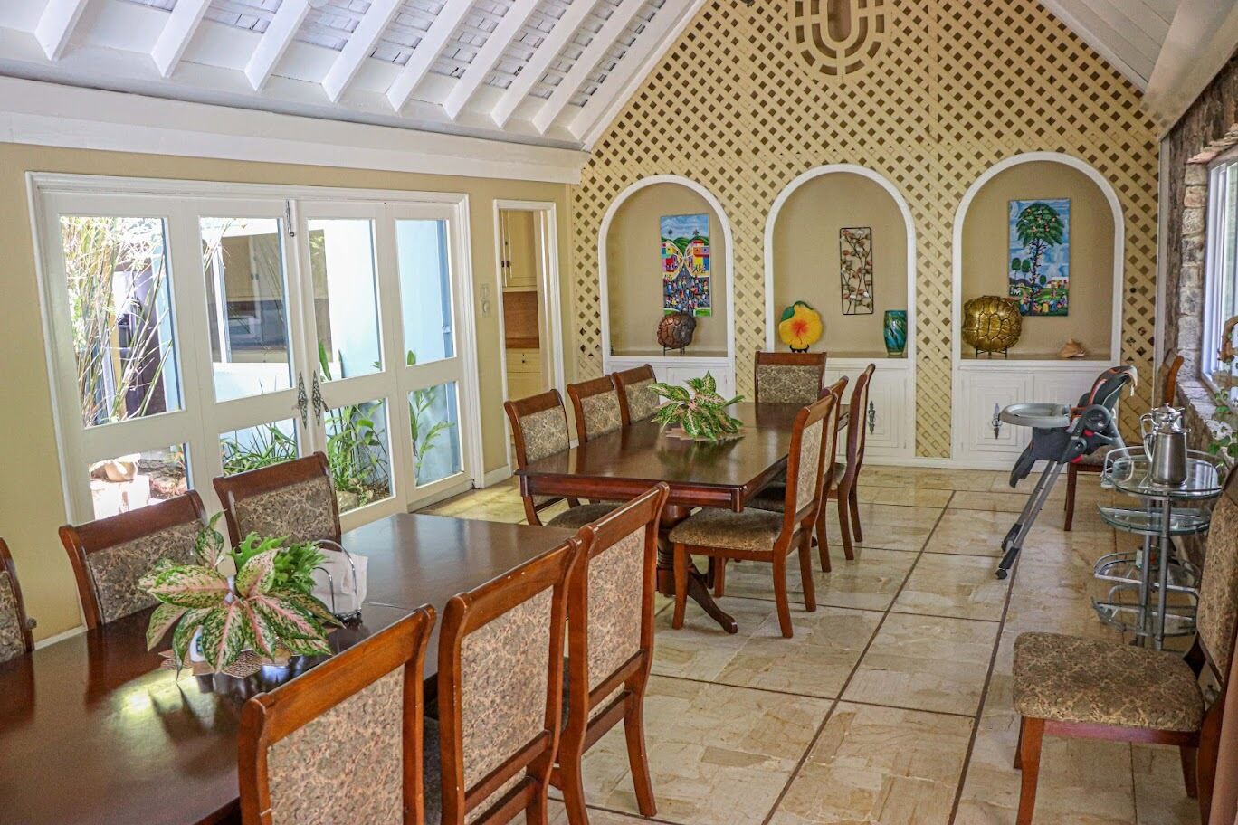A dining area with a large table and chairs, a ceiling with skylights, and a patterned wall with artwork.