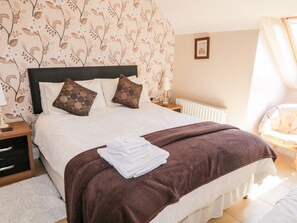 A neatly made bed with a brown blanket, white pillows, and a folded white towel on the bed.