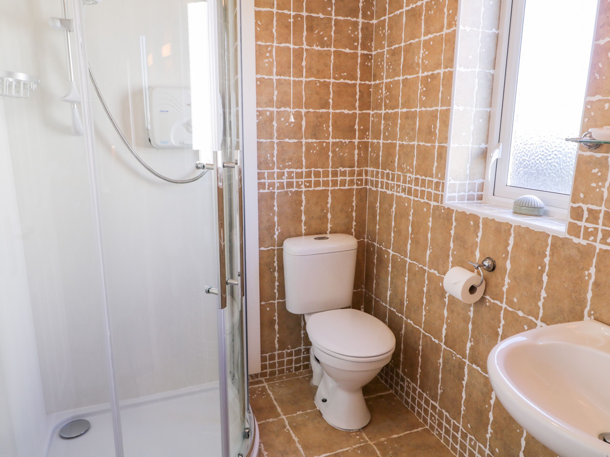 A bathroom with a glass-enclosed shower, a toilet, and a sink.