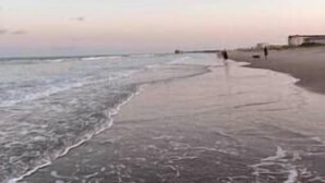 Una playa con cielo despejado y olas suaves.