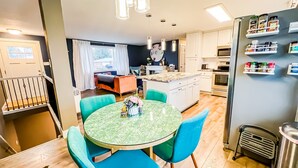 A modern kitchen with a dining area, featuring a round table with chairs, a built-in oven, and a refrigerator with spice racks. - Quiet Clean Pet Friendly Close to Downtown Sleeps 10 (Colorado Springs)