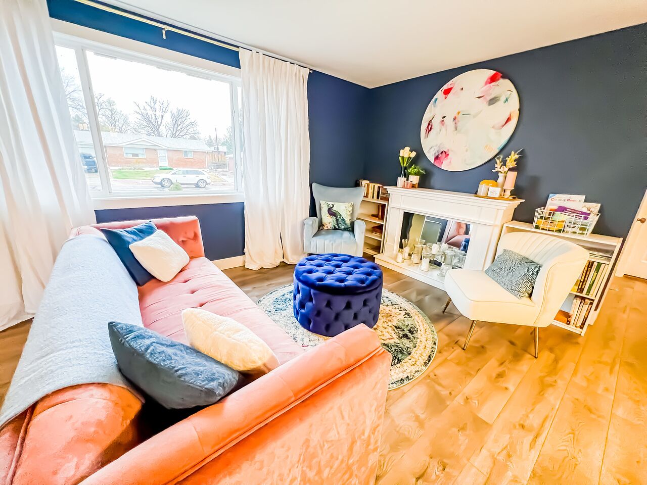 Uma sala de estar com sofá, pufe e lareira.