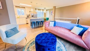 A modern living room with a white armchair, a blue ottoman, and a pink sofa. - Quiet Clean Pet Friendly Close to Downtown Sleeps 10 (Colorado Springs)