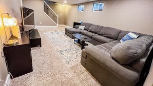 A living room with a sectional sofa, a coffee table, and a lamp. - Quiet Clean Pet Friendly Close to Downtown Sleeps 10 (Colorado Springs)