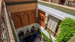 Un patio con una fuente, arcos y un balcón con vistas al jardín.