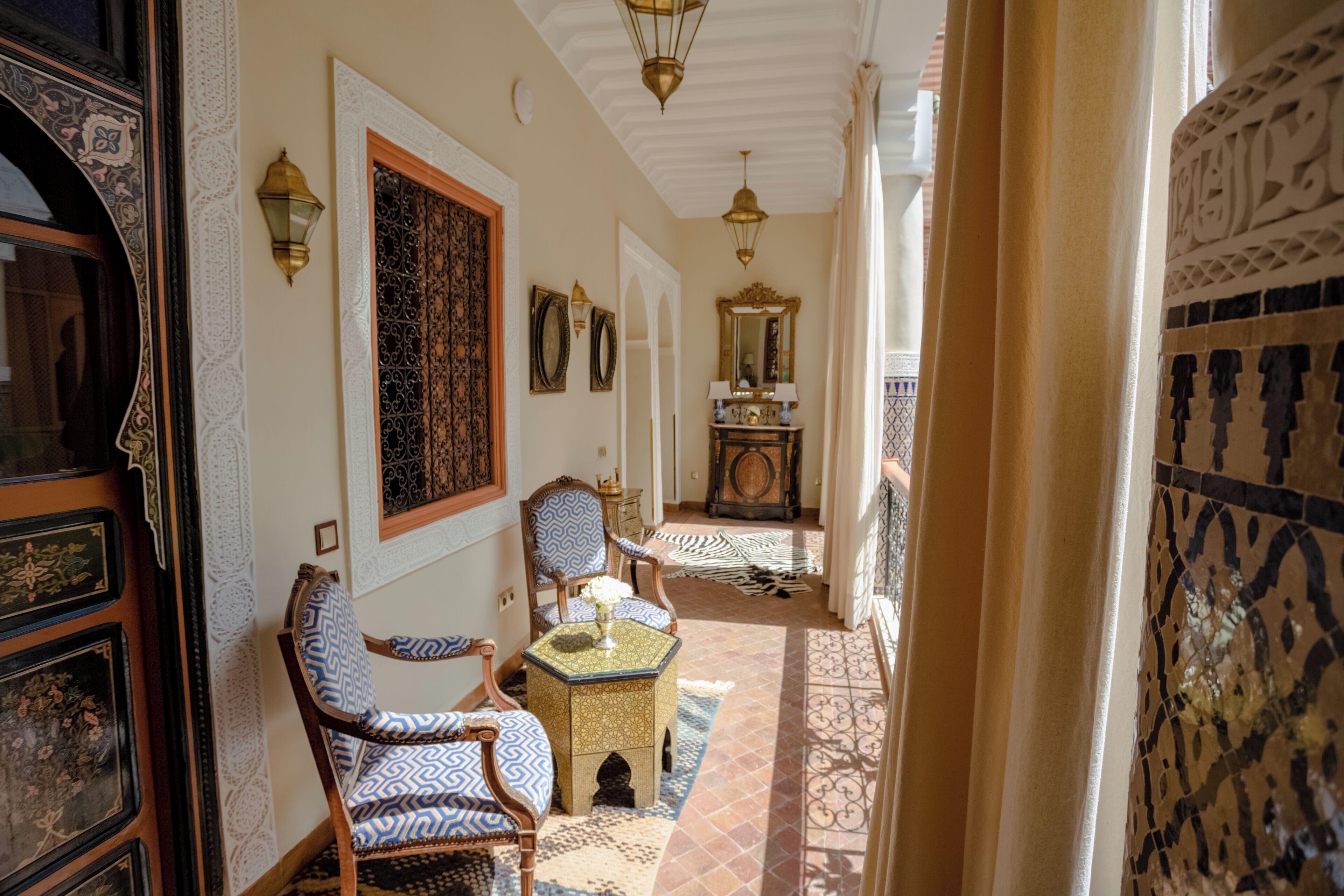 A hallway with ornate doors, patterned rugs, and traditional furniture.