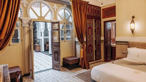 Una habitación con cama, piano, candelabro y vistas al exterior.