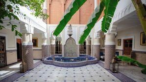 Un patio con una fuente, baldosas decoradas y columnas.