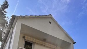 Um edifício de dois andares com varanda, garagem e céu limpo.
