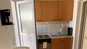 Cozinha compacta com armários de madeira, fogão, pia e cafeteira.