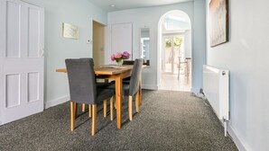 Un comedor con mesa y sillas de madera, un florero y vistas al exterior a través de un arco.