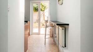 Un pasillo estrecho con tragaluces, una zona de cocina con mostrador y taburetes, y una puerta que da a un espacio exterior.