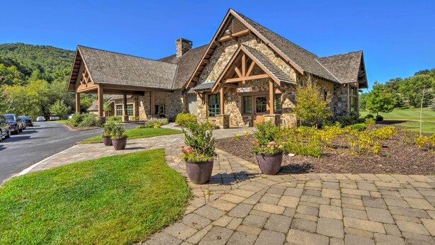 A stone building with a stone roof and wooden beams, surrounded by a well-maintained lawn and potted plants. - Charming Condo on Sky Valley Golf Course! (Sky Valley)