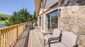 A wooden deck with outdoor furniture, a stone wall, and a glass door leading to a covered area. - Charming Condo on Sky Valley Golf Course! (Sky Valley)