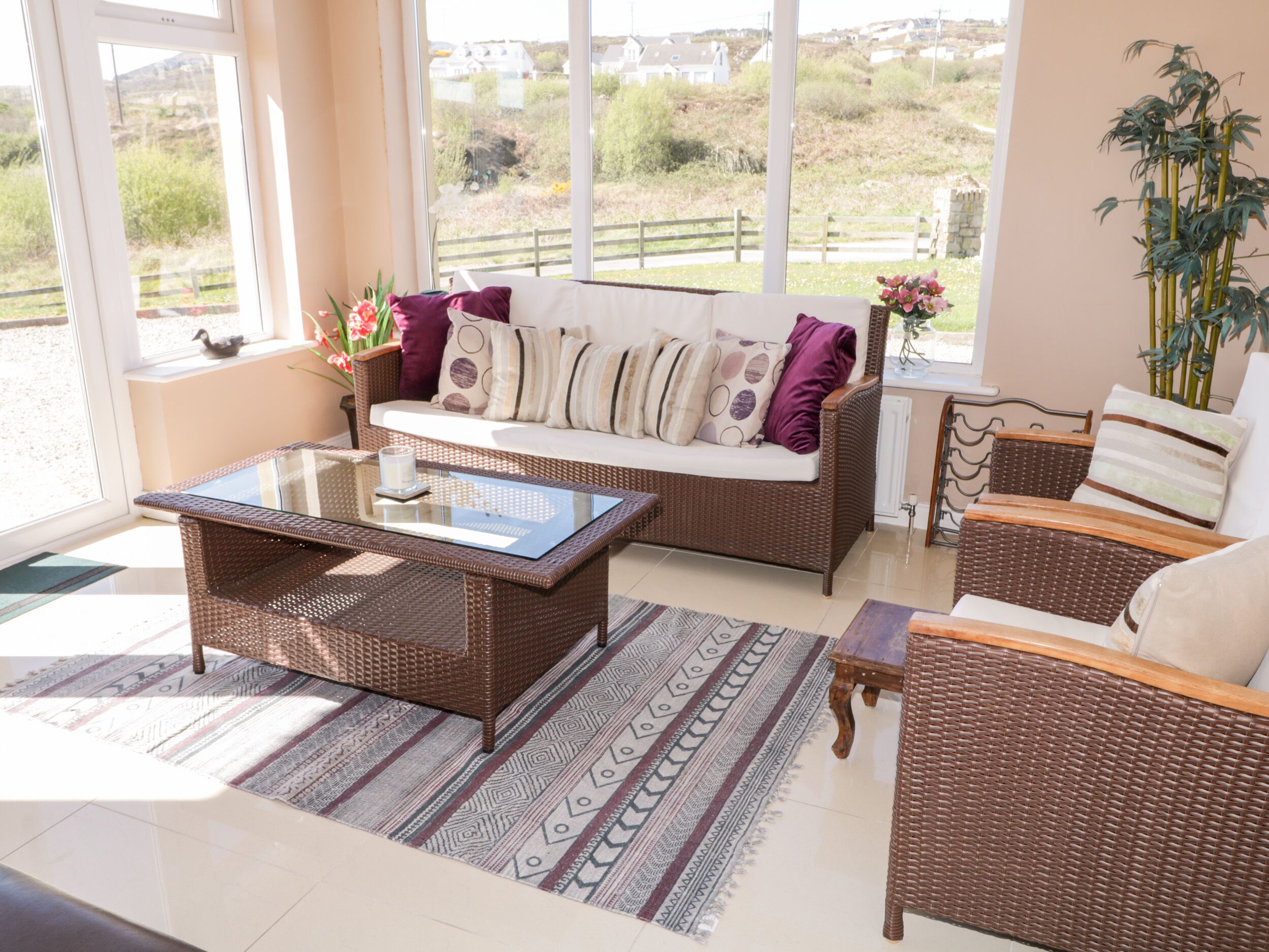 Un salón acogedor con muebles de mimbre, una mesita de cristal y vistas al campo.