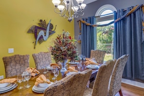Enjoy meals in this beautifully set dining area with a chandelier, large window, and decorative piece.