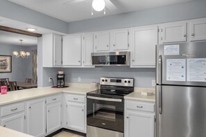 A modern kitchen with white cabinets, stainless steel appliances, and a dining area with a table and chairs.